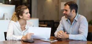 2_positive-young-employee-showing-report-business-colleague
