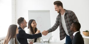 smiling-businessman-welcoming-new-partner-group-meeting-with-handshake